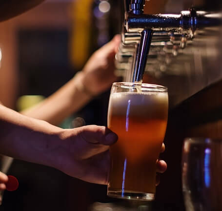 glass of beer filling up from the tap at a bar