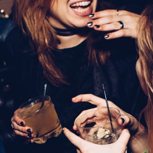two girls with drinks in hands laughing